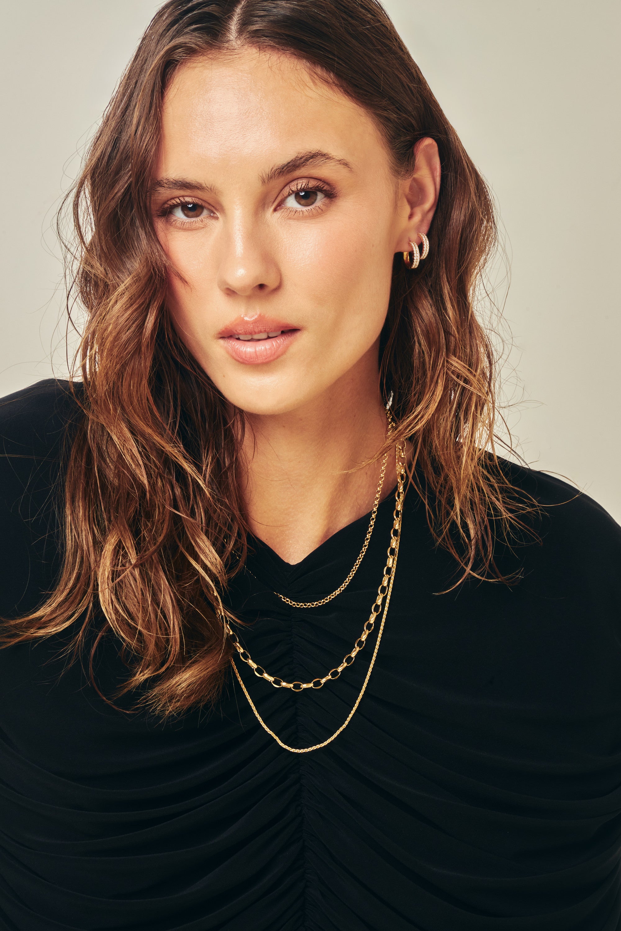 Three Alexander Kade gold chains layered, worn by a model