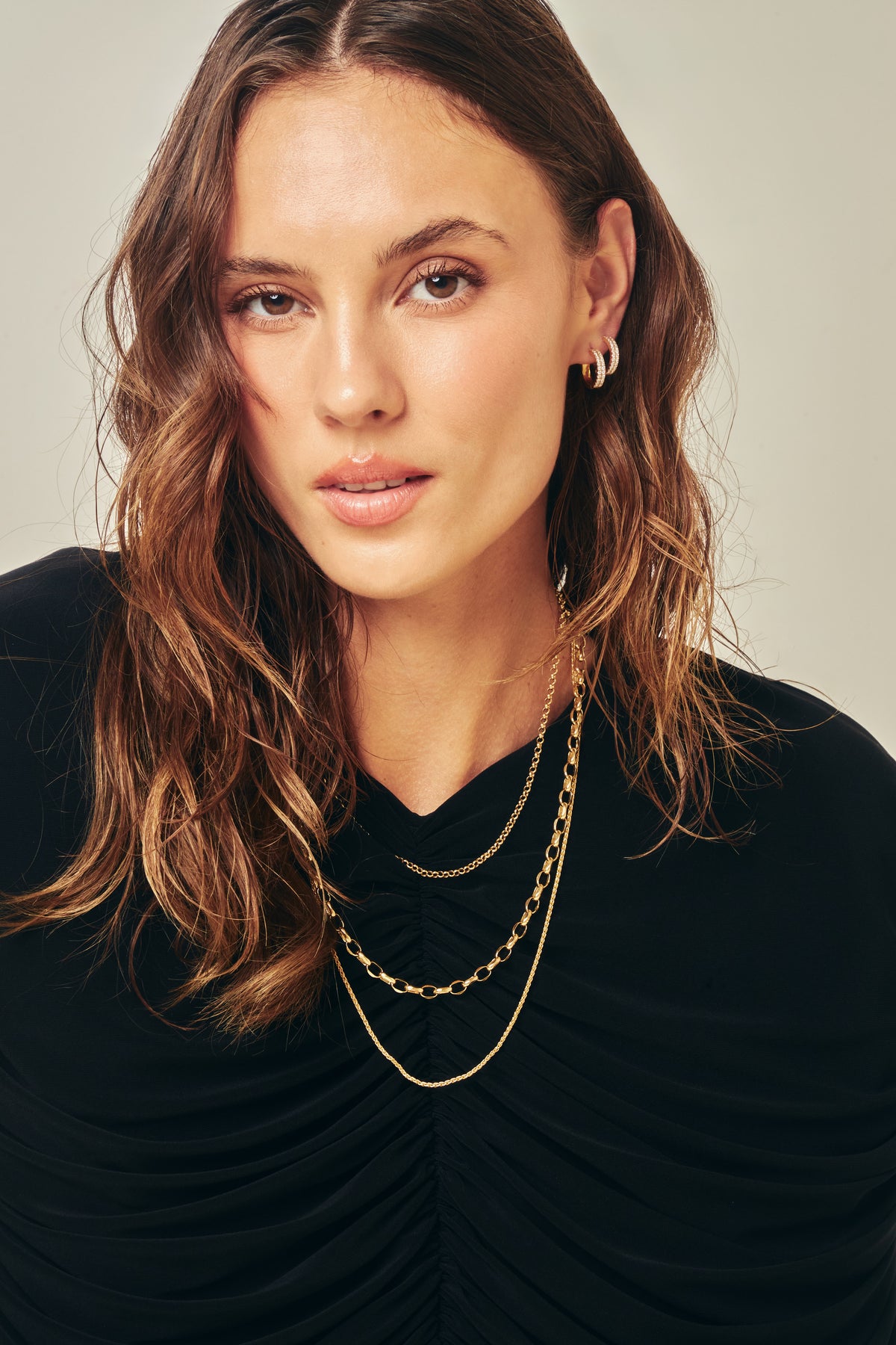 Three Alexander Kade gold chains layered, worn by a model